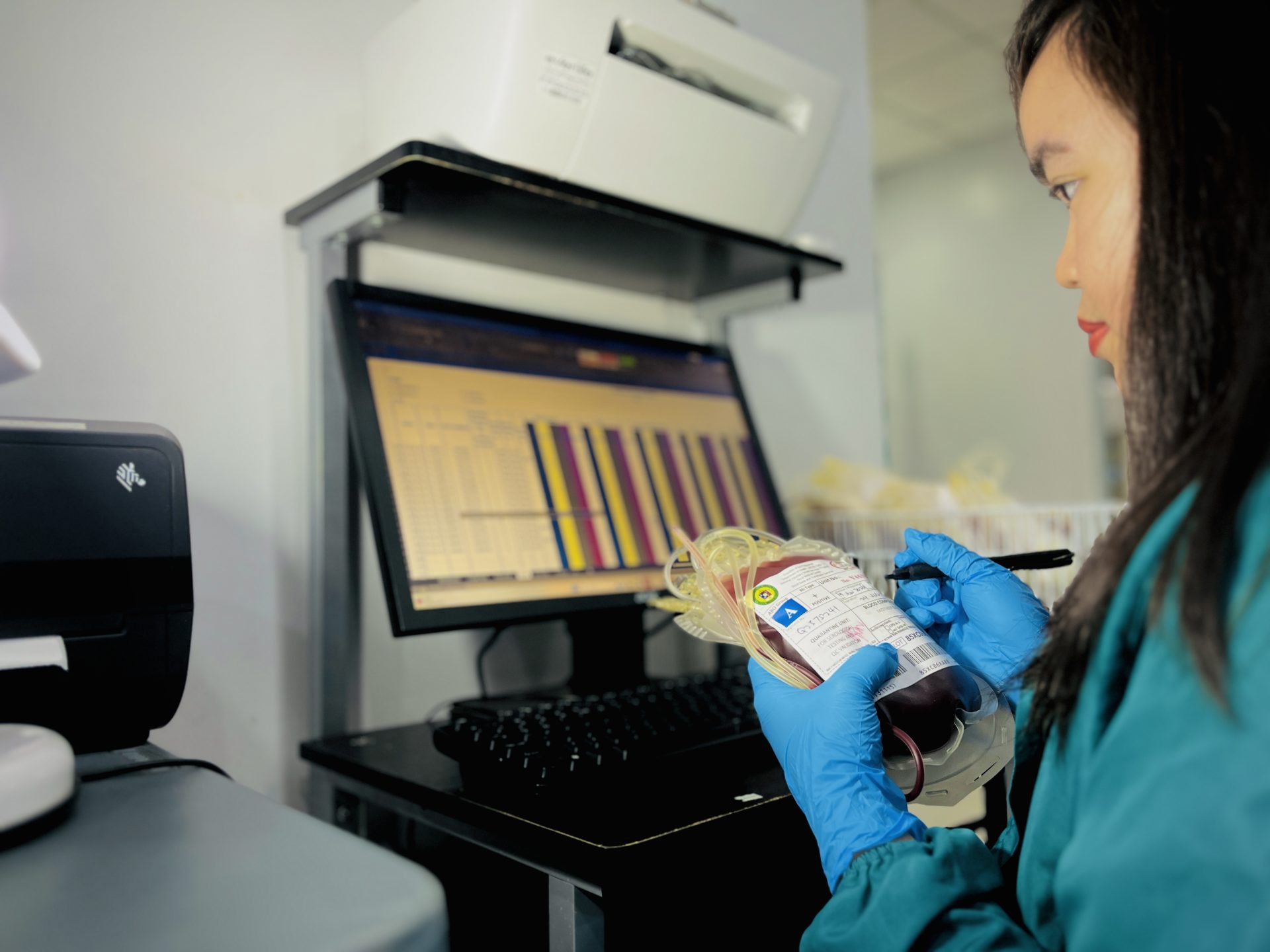 A laboratory staff member inspecting a prepared blood unit